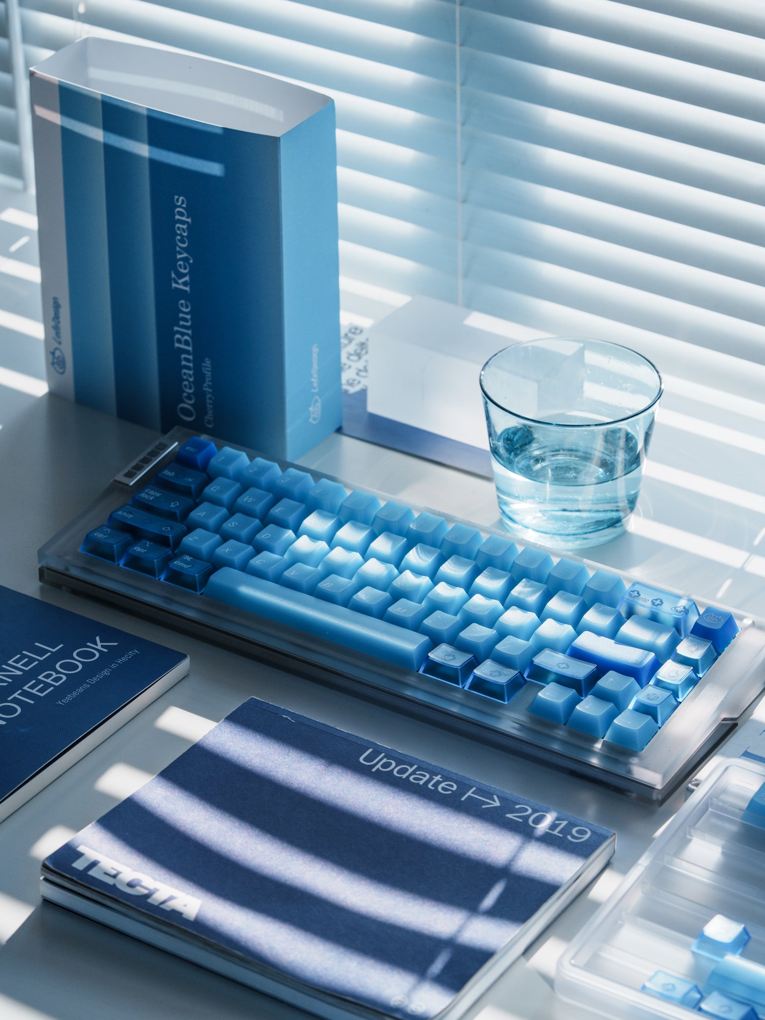 Ocean Blue keycaps and packaging in a sunlit desk setting